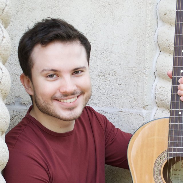 Aaron Goldstein smiling, holding an acoustic guitar